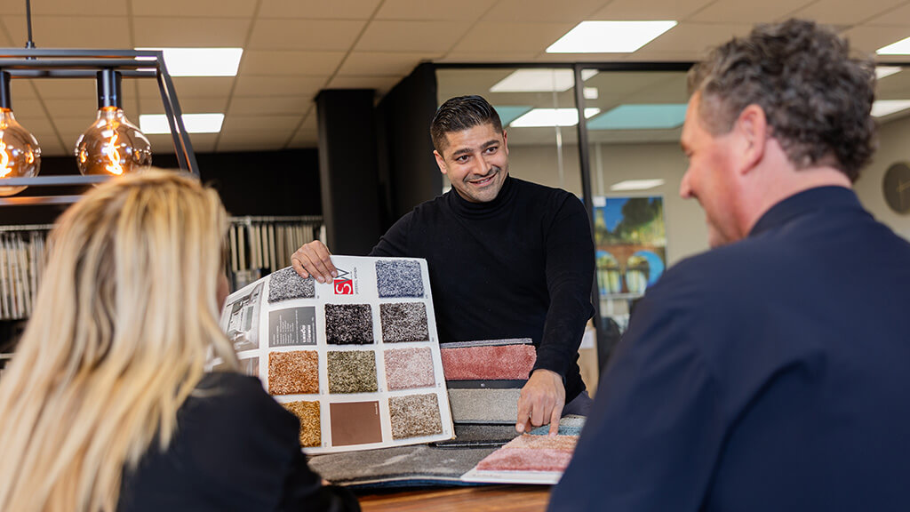 Adviseur toont stalen van pvc tegels aan klant in showroom