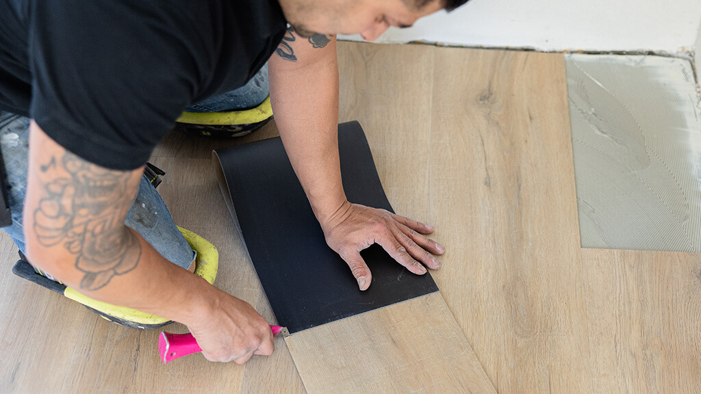 Close-up van het leggen van een pvc houtlook vloer door vakman